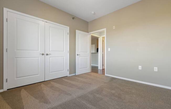 A room with two white doors and a carpeted floor.