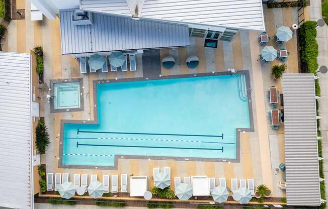 An aerial view of a swimming pool surrounded by lounge chairs and umbrellas.
