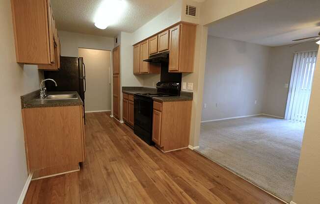 an empty kitchen and living room with wood flooring and
