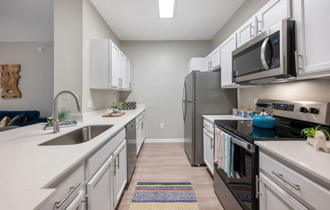 an open kitchen with white cabinets and stainless steel appliances and a microwave