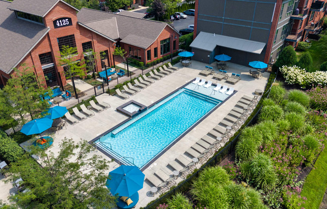 a resort style swimming pool in front of a hotel with umbrellas at Hayden Lofts, Dublin