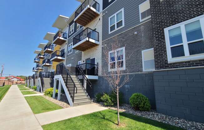 an exterior view of an apartment building with grass and a sidewalk