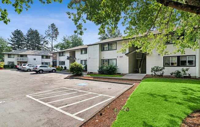 A parking lot in front of a building with a green lawn.