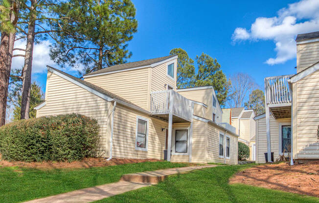 a group of houses with trees in the background and a sidewalk