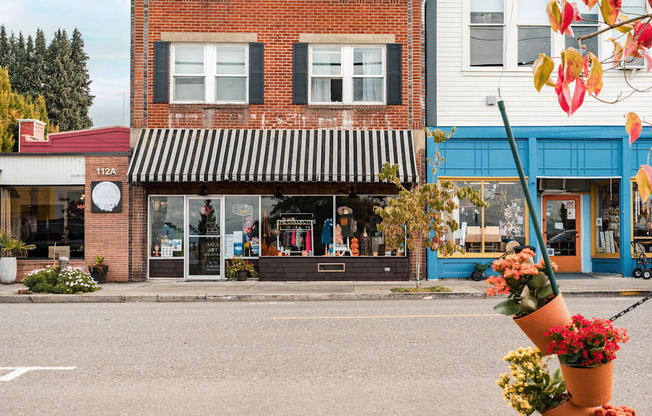 A flower pot is in the foreground of a street scene with a storefront in the background.