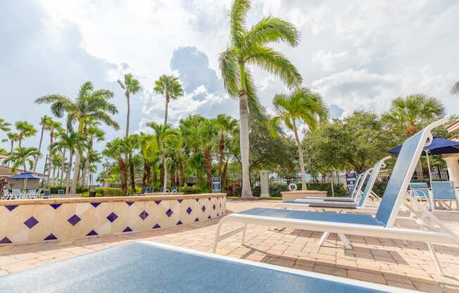 a resort style pool with chaise lounge chairs and palm trees in the background at Heritage Bay, Jensen Beach, 34957