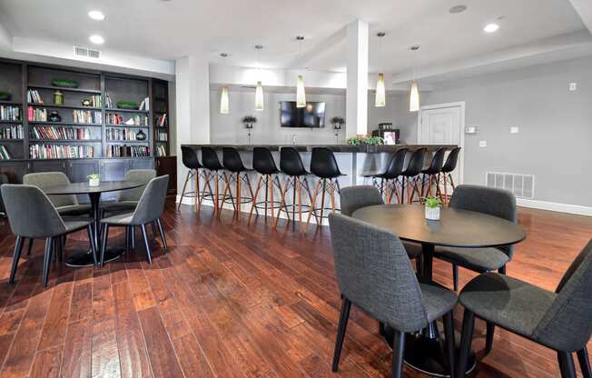 a large room with hardwood floors and a bar with chairs and tables