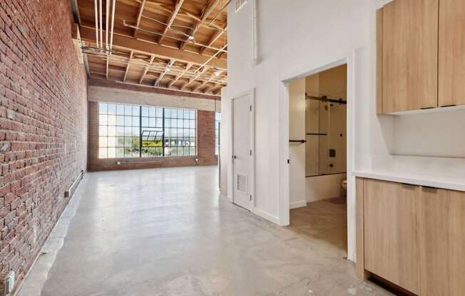 A room with a brick wall and wooden cabinets.