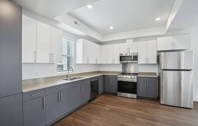 A modern kitchen with wooden floors and stainless steel appliances.