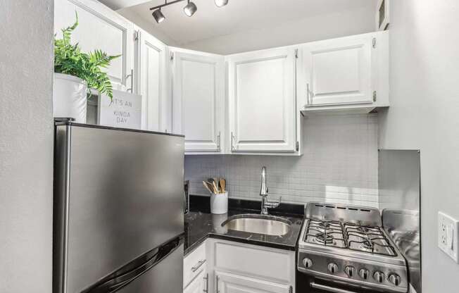 A kitchen with a stainless steel refrigerator and a stove top oven.