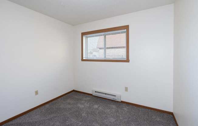 an empty room with a window and carpet. Fargo, ND Pacific South Apartments