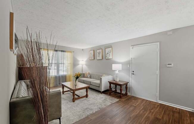 A living room with a couch, a table, and a vase of dried flowers.