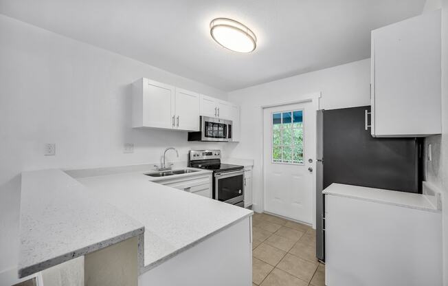 a kitchen with white counters and a black refrigerator