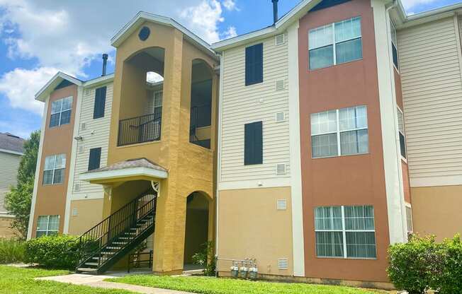 an exterior view of an apartment building with stairs and a yard