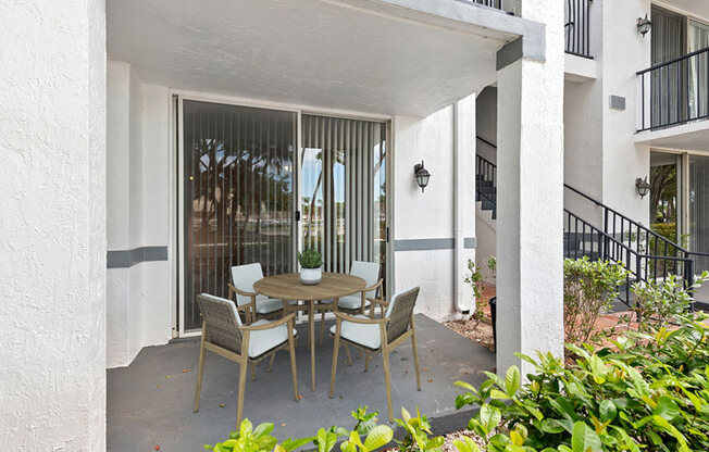 A patio with a table and chairs is surrounded by white columns.