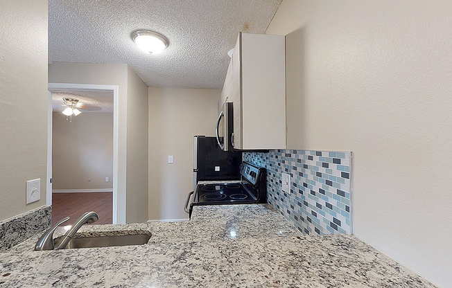 Modern kitchen with granite countertops and stylish mosaic backsplash, ideal for culinary enthusiasts.