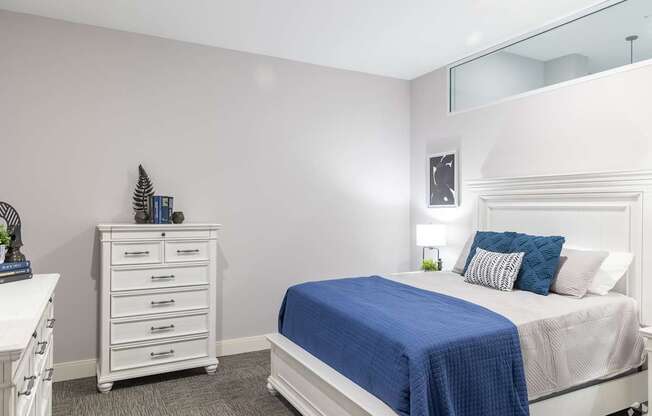 A bedroom with a white bed and a blue blanket.