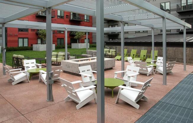 A patio with white chairs and tables under a white canopy.