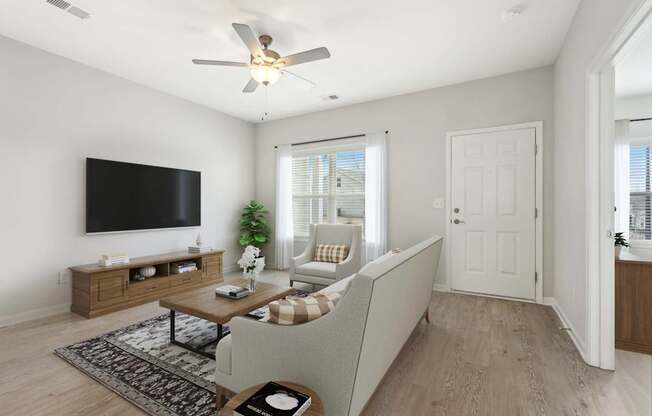 A living room with a couch, a television, and a ceiling fan.