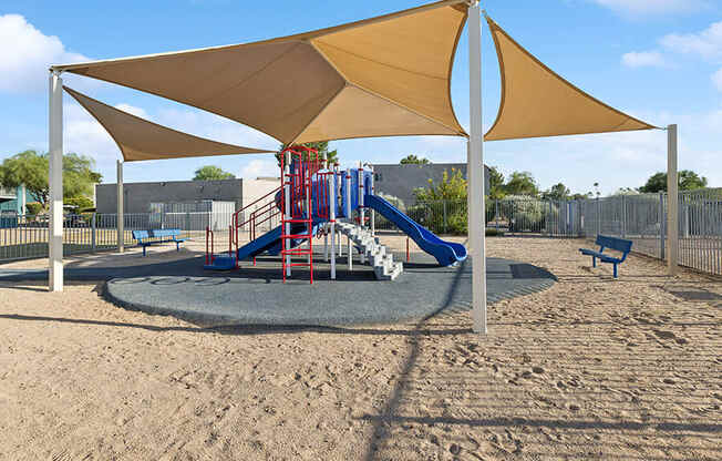 Community Playground with Slide and Tan Canopy at Tanque Verde Apartments located in Tucson, AZ.