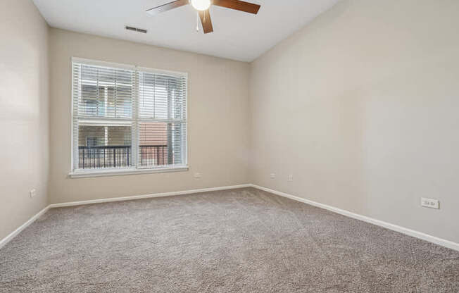 A room with a ceiling fan and a window with blinds.