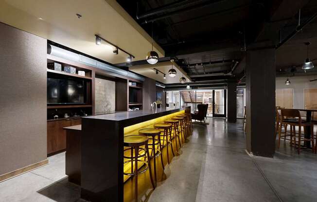 A long bar with stools is in the middle of a room.