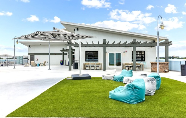 A white building with a black roof and a white awning with a green lawn in front.
