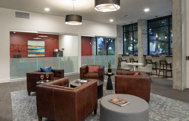 A modern living room with brown leather furniture and a grey ottoman. at Ravello Apartments, Washington