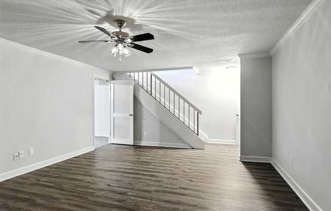 A room with a ceiling fan and wooden floors.