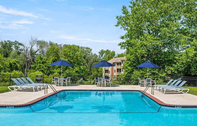A swimming pool surrounded by lawn chairs and umbrellas.