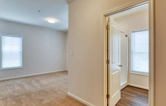 a living room with a door and a hallway to a bedroom