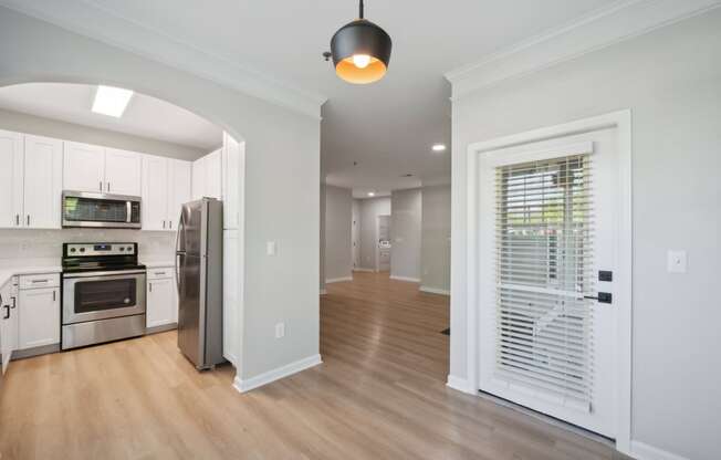 a renovated kitchen and living room with white cabinets and a door to a hallway