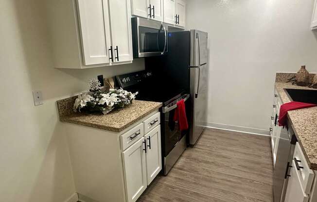 A kitchen with white cabinets and a black fridge at Willow Tree Apartments, California, 90505