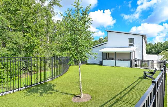 a backyard with a grassy area and a white house in the background