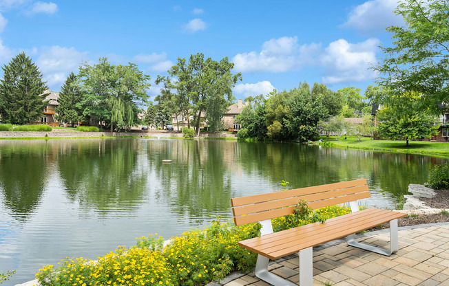 a bench overlooking a lake with houses and trees in the background at The Hinsdale, Illinois, 60521