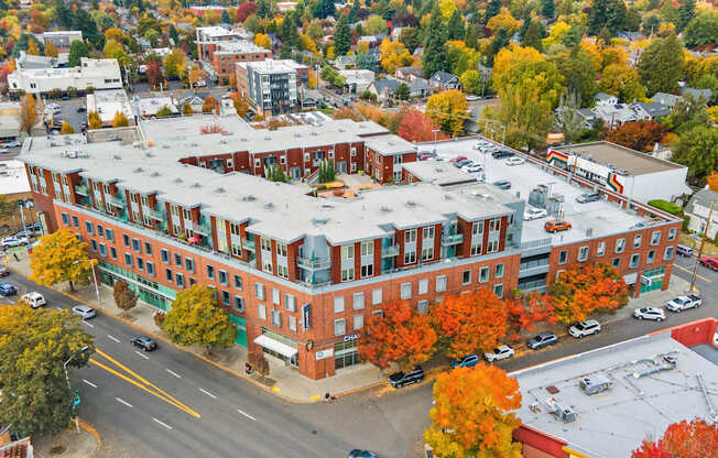 A large red brick building with a green roof in the middle of a street.