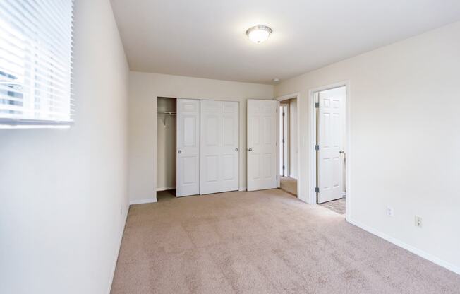 a spacious living room with white walls and carpet and white doors