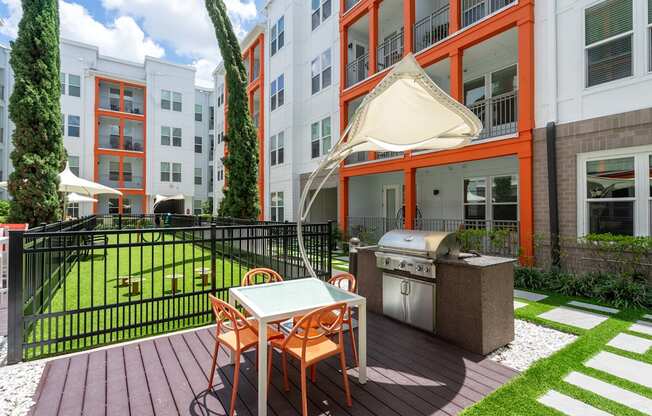 A patio with a table and chairs and a grill.
