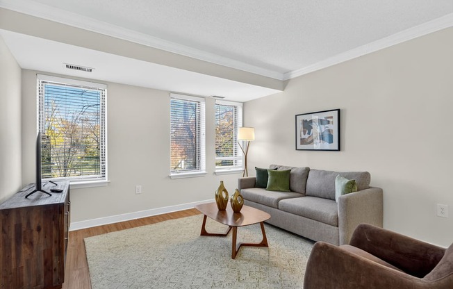 A living room with a grey couch, a wooden coffee table, and a brown armchair.