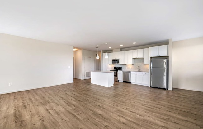 an empty living room and kitchen with a wood floor