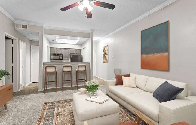 a living room with a white couch and a kitchen in the background