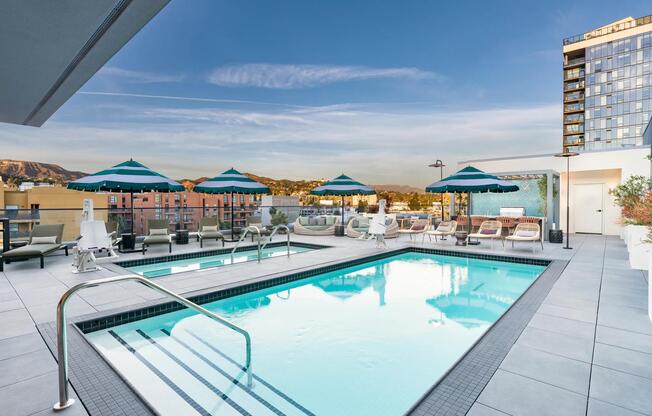 The rooftop pool, designed in a resort-style, features comfortable daybeds and shaded areas for relaxation.