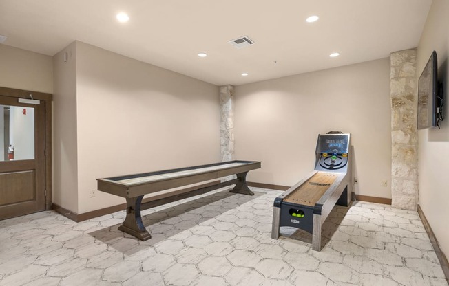a game room with a shuffleboard table and a bench