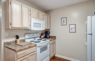 A kitchen with a white stove and white microwave.