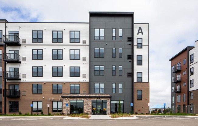 A modern apartment building with a mix of white and dark exterior walls.