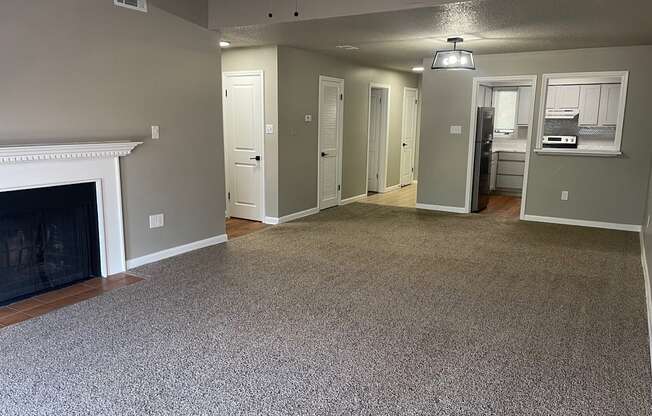 A living room with a fireplace and grey carpet.