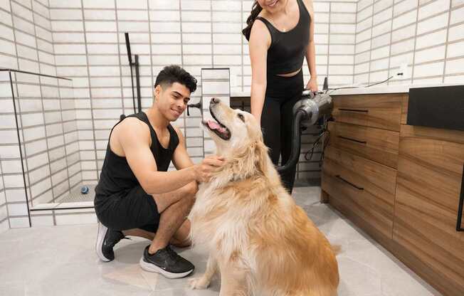 A man and woman petting a dog in a tiled room.