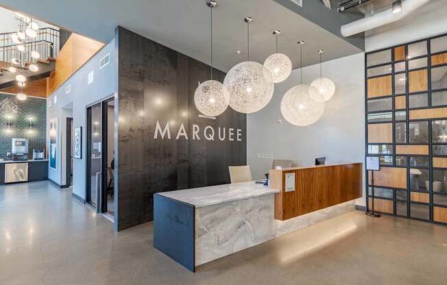A reception area with a white reception desk and a wall with the word MARQUEE on it.
