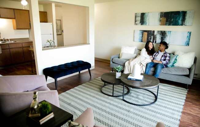 two people sitting on a couch in a living room at Sutton Hill Apartments, Des Moines, IOWA