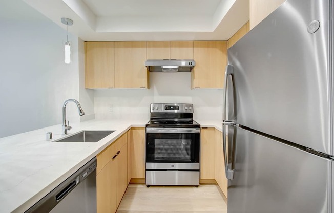A modern kitchen with a stainless steel refrigerator, sink, and oven.